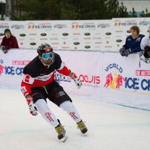 Ice cross competition featuring multiple athletes racing on a snowy, icy track with obstacles and sharp turns.