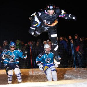 A man performing an ice cross jump, soaring through the air with determination and skill.