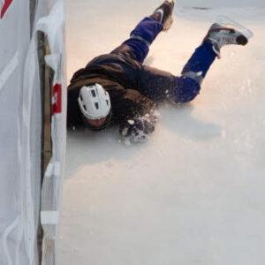 A person losing balance and falling off a ramp onto a slippery ice surface, capturing a moment of unexpected descent.