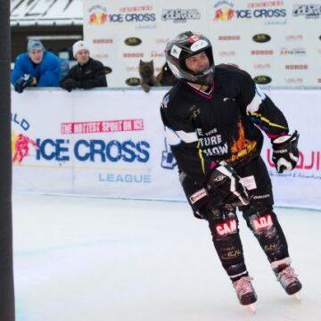 A man on skis descends a ramp in an ice cross event, showcasing speed and skill in a thrilling winter sport.